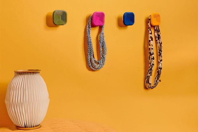 Quatre patères carrées colorées - fixées sur un mur jaune